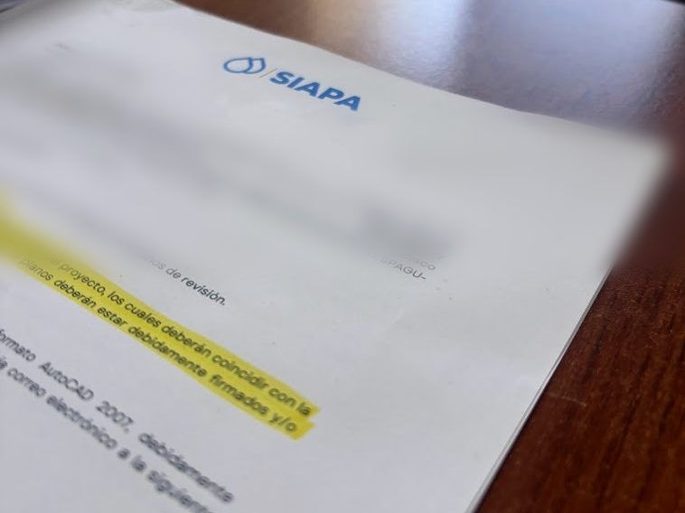 Oficio de revisión de expediente técnico ante SIAPA sobre un escritorio