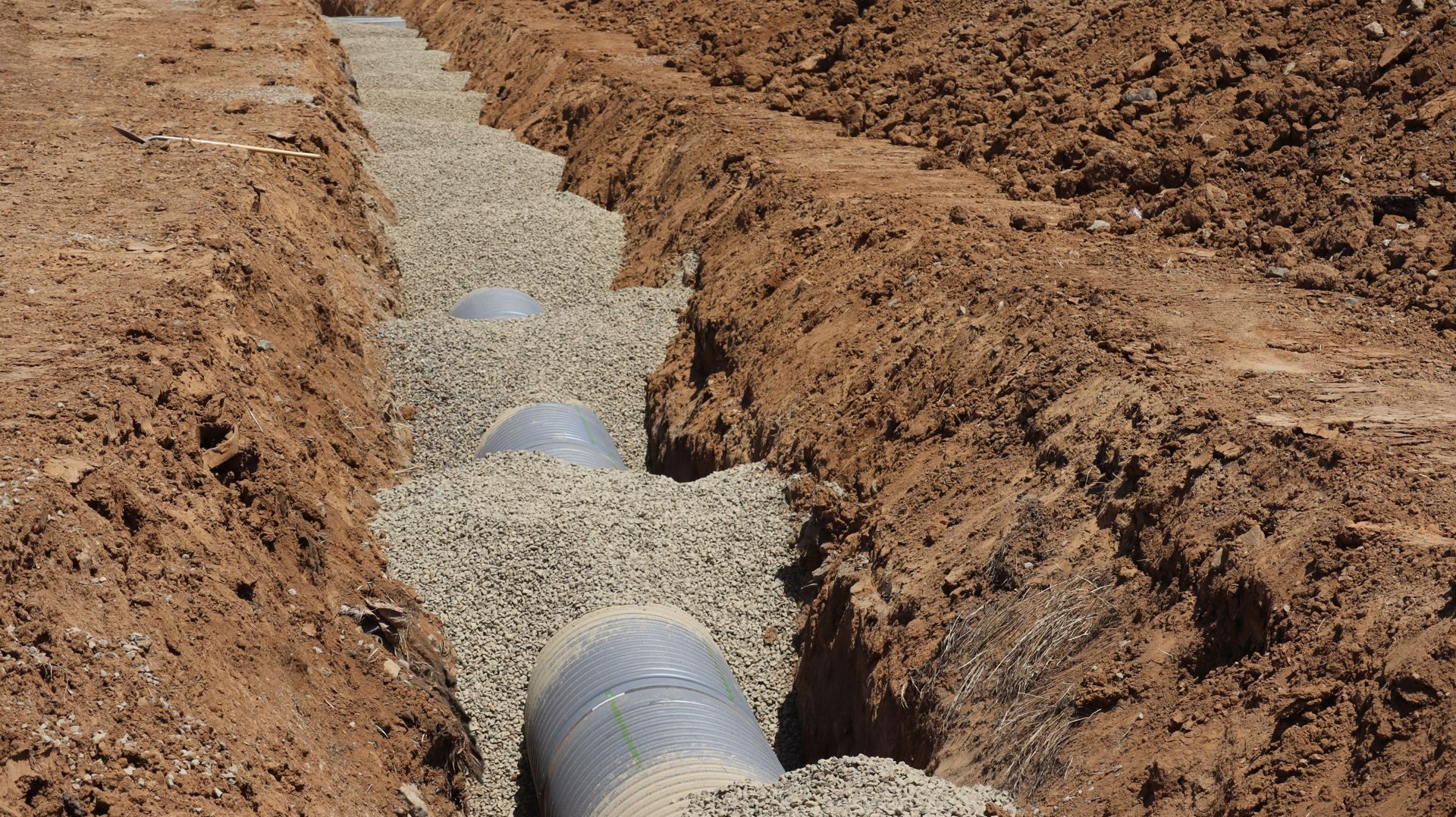 Tubería nueva instalada sobre cama de grava en una zanja de red de agua potable